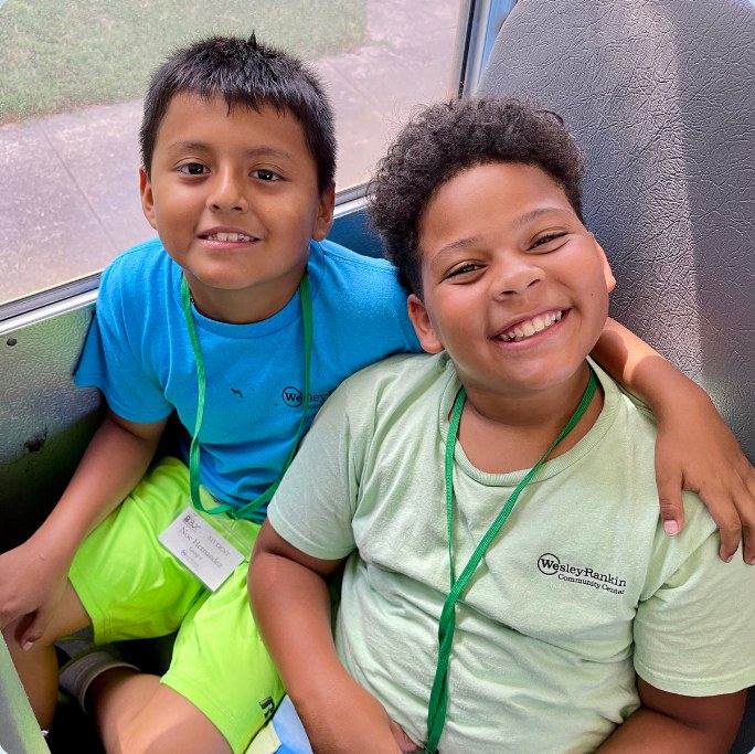 Two young participants smiling with their arms around each other.